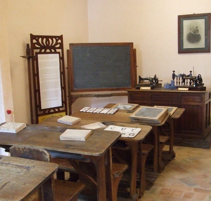 Aula "Metodo Montessori" ricostruita con materiali originali a Città di Castello: in alto il ritratto del barone Leopoldo Franchetti che, con la giovane moglie Alice, finanziò la Montessori