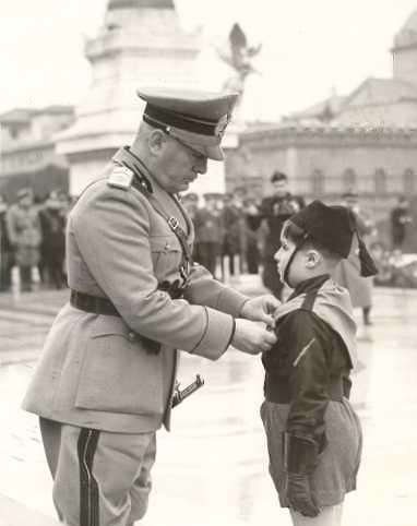 Benito Mussolini, di fronte all'Altare della Patria, premia un giovanissimo balilla durante una cerimonia