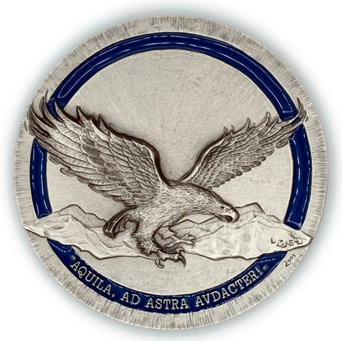 Un'aquila in volo nel cielo sopra le montagne, ad ali spiegate: questa iconografica e il motto latino AQUILA, AD ASTRA AVDACTER! caratterizzano presso l'Accademia Aeronautica i corsi che portano il nome del rapace