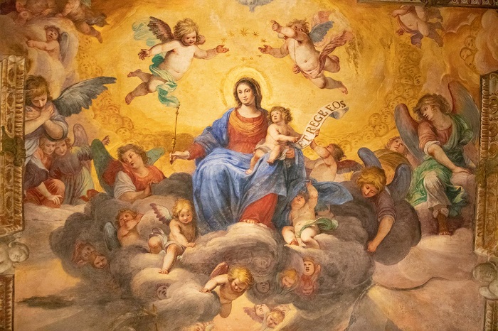 La Vergine in gloria sulle nubi, col Bambino in braccio e attorniata da cherubini, dipinta sulla volta della Cappella Ducale di Genova: Gesù regge il cartiglio con il motto ET REGE EOS