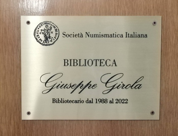 La targa apposta all'ingresso della biblioteca della Società numismatica italiana, intitolata a Giuseppe Girola, per trentaquattro anni curatore del patrimonio librario del sodalizio